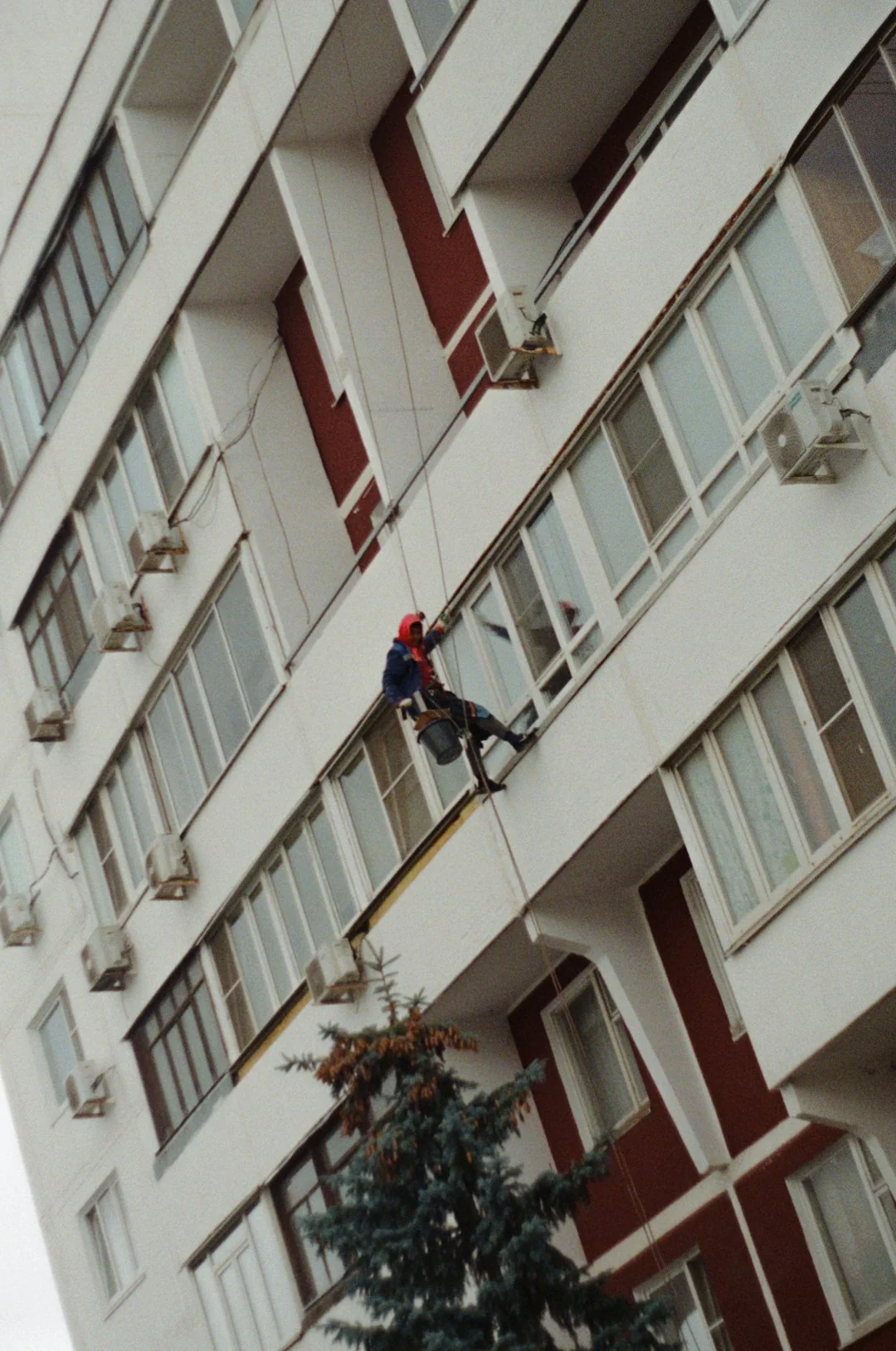 High-rise window washers in safety gear cleaning a skyscraper facade.